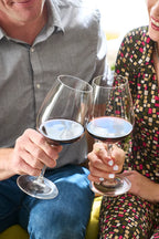Smiling couple toasting with glasses of 2023 HALL Craig's Cabernet Sauvignon