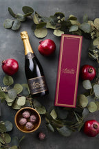 Image of the Michel Foch Blanc de Blancs 2015 holiday gift set featuring a bottle of the  Michel Foch Blanc de Blancs 2015 and an elegant branded gift box. The image is decorated with pomegranates, truffles and garland.